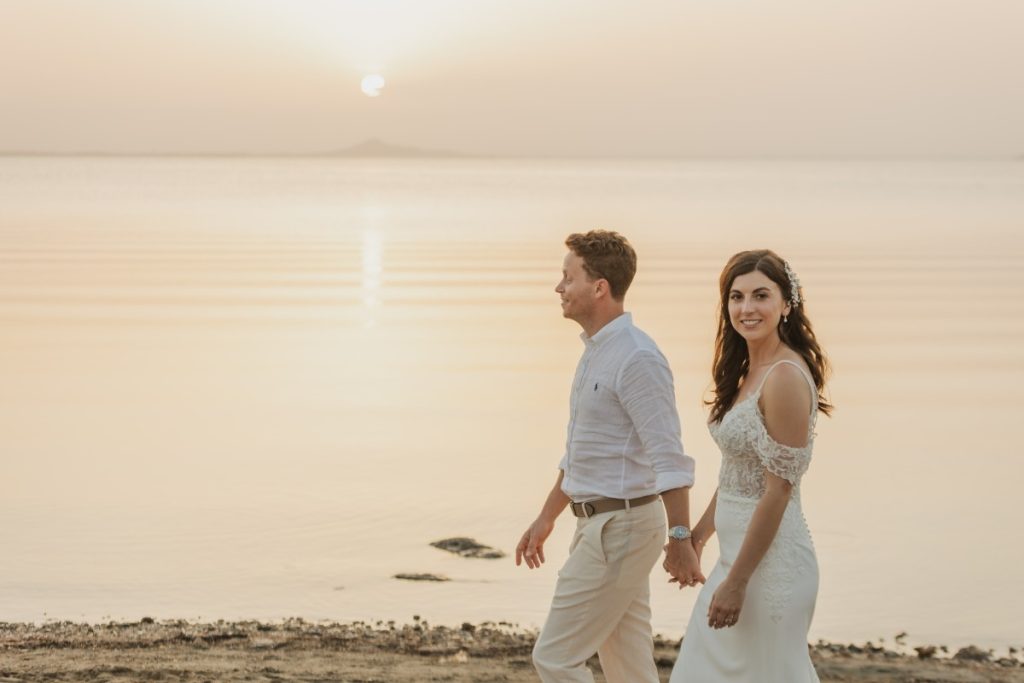 Sunset at La Manga del Mar Menor, Spain — bride and groom walking hand in hand on the beach, warm golden light — destination wedding photographer Alicante & Costa Blanca.