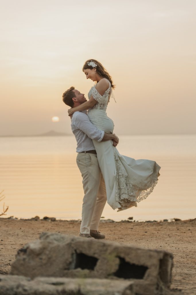 Couple ater the ceremony walking on the sunset on the beach